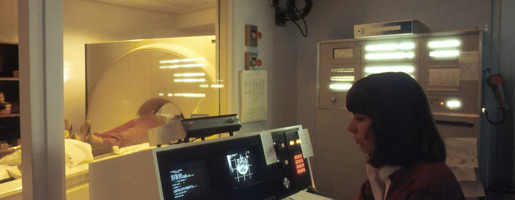 Tecnóloga trabajando en la consola de un tomógrafo
